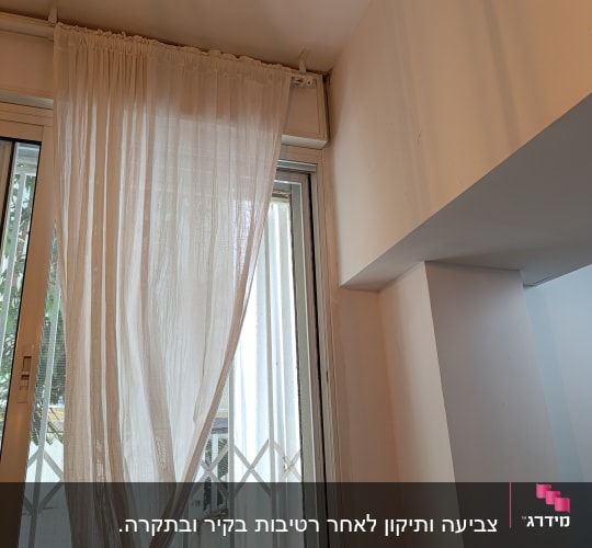 קיר צבוע בלבן ליד חלון עם וילון לבן